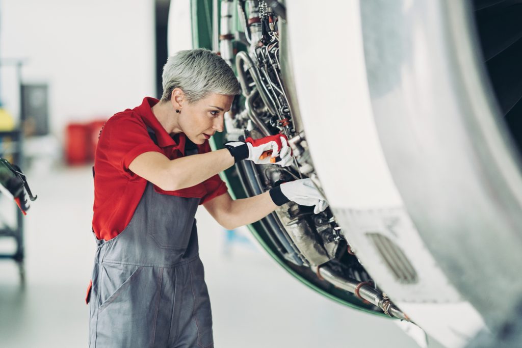 Female mechanic working on airplane engine